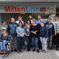 Gruppenfoto mit vielen Menschen unter dem Schriftzug "MittenDrin"