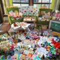 Ein Raum voll mit Geschenken und Kinderzeichnungen auf Fußboden und Sesseln