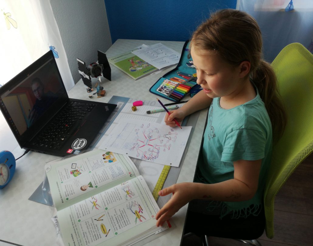 ein Schulmädchen am Schreibtisch mit Schulbüchern und Laptop