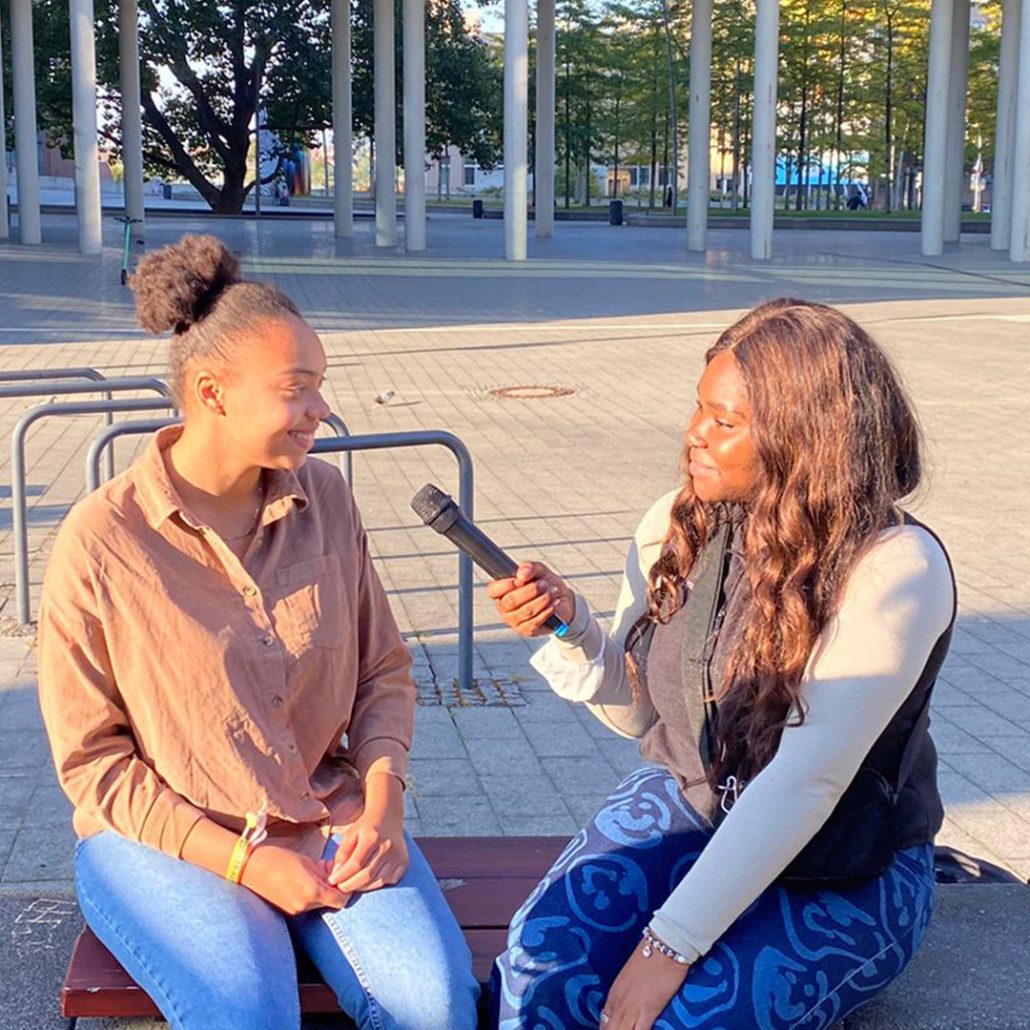 Foto von zwei jungen Frauen mit Mikrofon in Interviewsituation