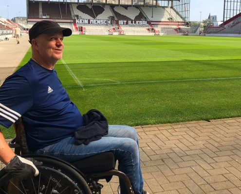 Ein Mann im Rollstuhl steht am Spielfeldrand des Millerntorstadions.