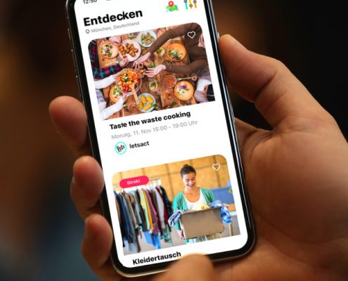 Hand hält Smartphone mit Ehrenamts-App Letsact