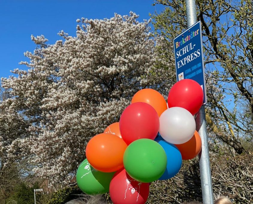 An einem Laternenmast sind das Schild "Brokstedter Schulexpress" sowie mehrere Luftballons angebracht.