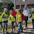 Eine junge Frau ist mit mehreren Kindern in Warnwesten zu Fuß unterwegs.