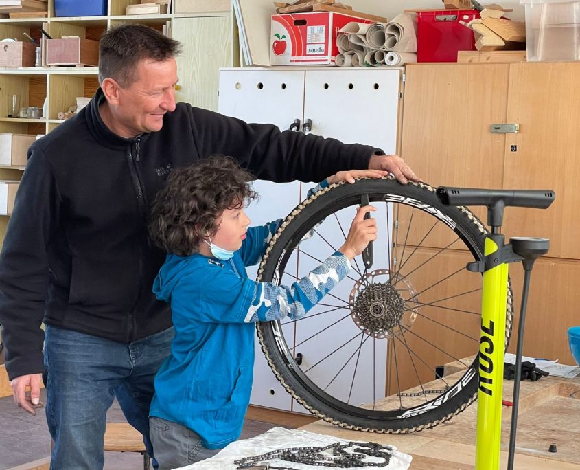 Ein Mann repariert zusammen mit einem Jungen einen Fahrradreifen.