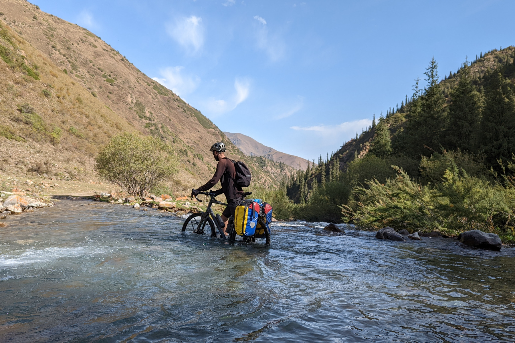 Falco Hüsson (More in Common e.V.) durchquert mit einem Mountainbike einen Fluss