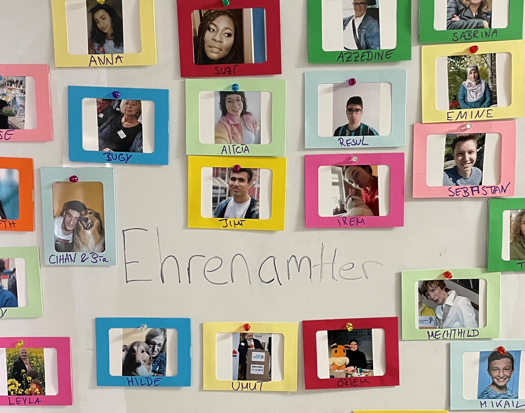 viele bunt eingerahmte Fotos von ehrenamtlich Engagierten an einer Wand