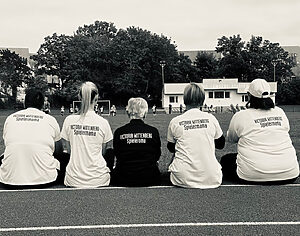 Zuschauerinnen beim Fußballspiel mit T-Shirts "Fußballmama" und "Fußballoma"