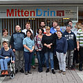 Gruppenfoto mit vielen Menschen unter dem Schriftzug "MittenDrin"