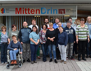 Gruppenfoto mit vielen Menschen unter dem Schriftzug "MittenDrin"