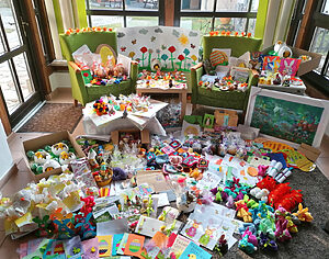 Ein Raum voll mit Geschenken und Kinderzeichnungen auf Fußboden und Sesseln