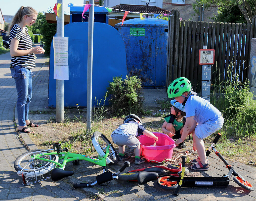 Junge Frau und drei Kleinkinder mit Fahrrädern