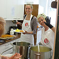 Zwei Frauen in Kochschürzen stehen hinter einem Topf