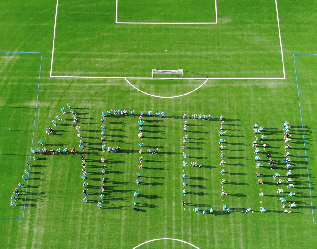 Viele Menschen, die auf einem Fußballfeld das Wort "Affeln" mit ihren Körpern gebildet haben