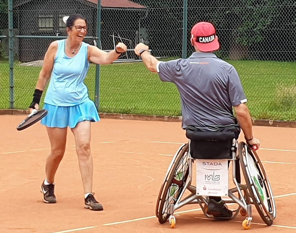 Tennisspielerin und Tennisspieler mit Handycap grüßen sich auf dem Platz