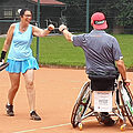 Tennisspielerin und Tennisspieler mit Handycap grüßen sich auf dem Platz