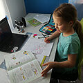 ein Schulmädchen am Schreibtisch mit Schulbüchern und Laptop