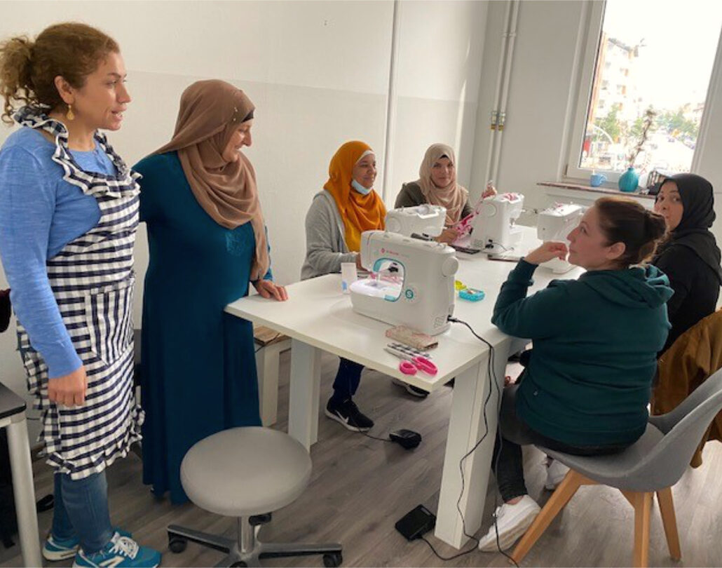 Frauen versammeln sich an einem Tisch mit Nähmaschinen