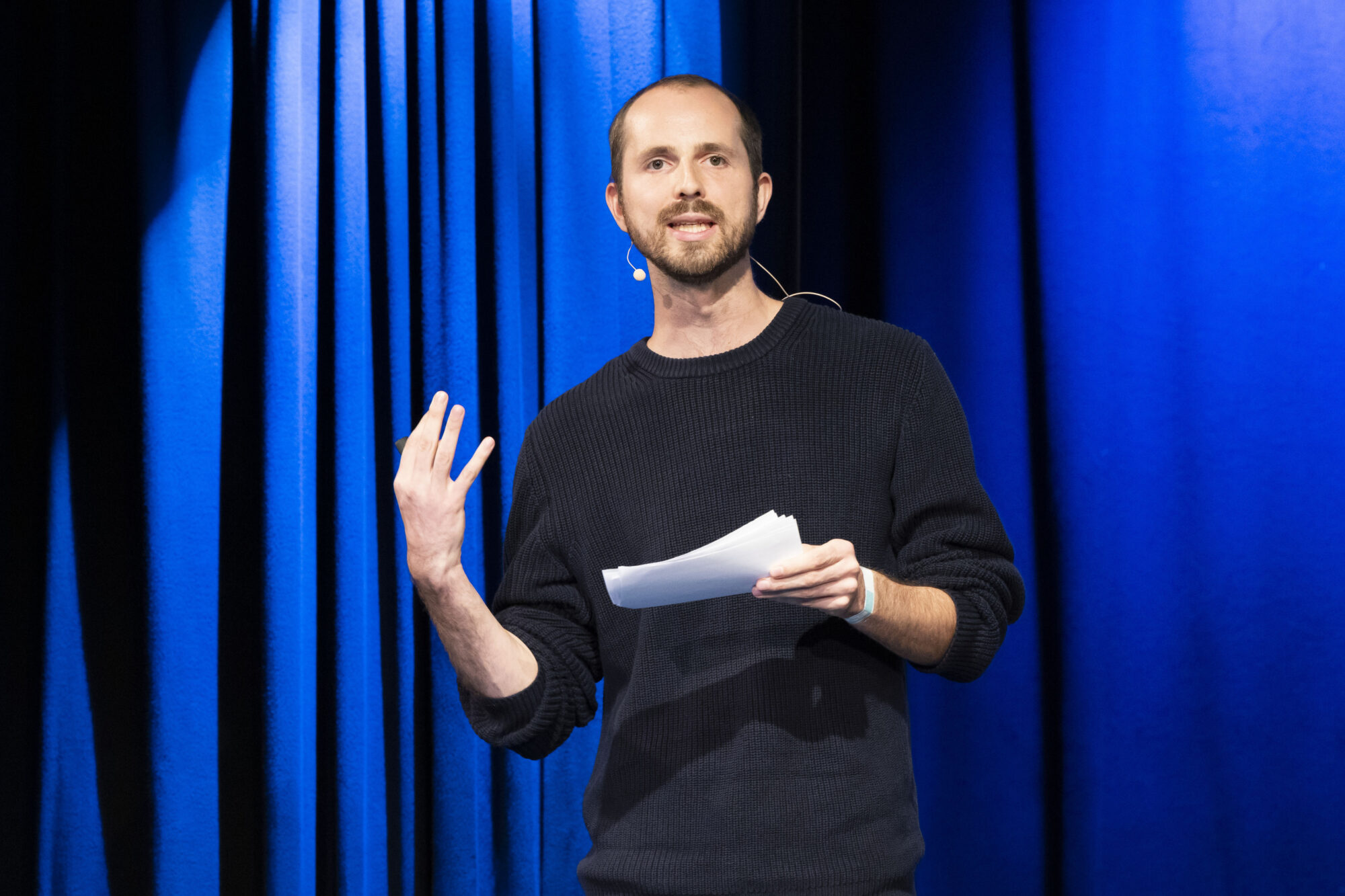 Falco Hüsson steht auf der Bühne und hält einen Science Slam