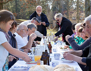 Menschen sitzen im Freien an einem gedeckten Tisch