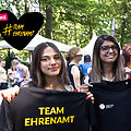 Foto von zwei jungen Frauen, die T-Shirts mit dem Logo der DSEE und dem Schriftzug Team Ehrenamt in die Hände halten. Gezeichnetes Herz mit dem Text Danke #TeamEhrenamt