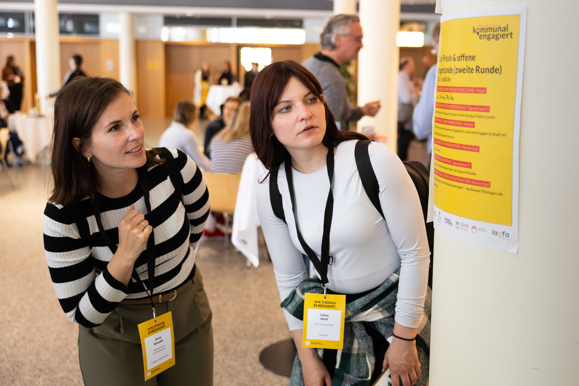 Zwei Teilnehmerinnen studieren das Programm der der Tagung #kommunalEngagiert