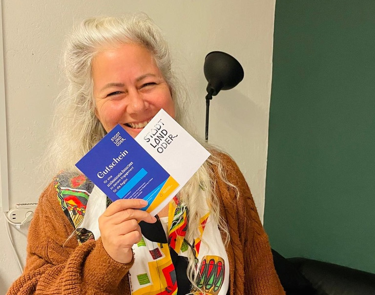Eine Frau hält eine Broschürfe "Stadt Land Oder" in die Kamera