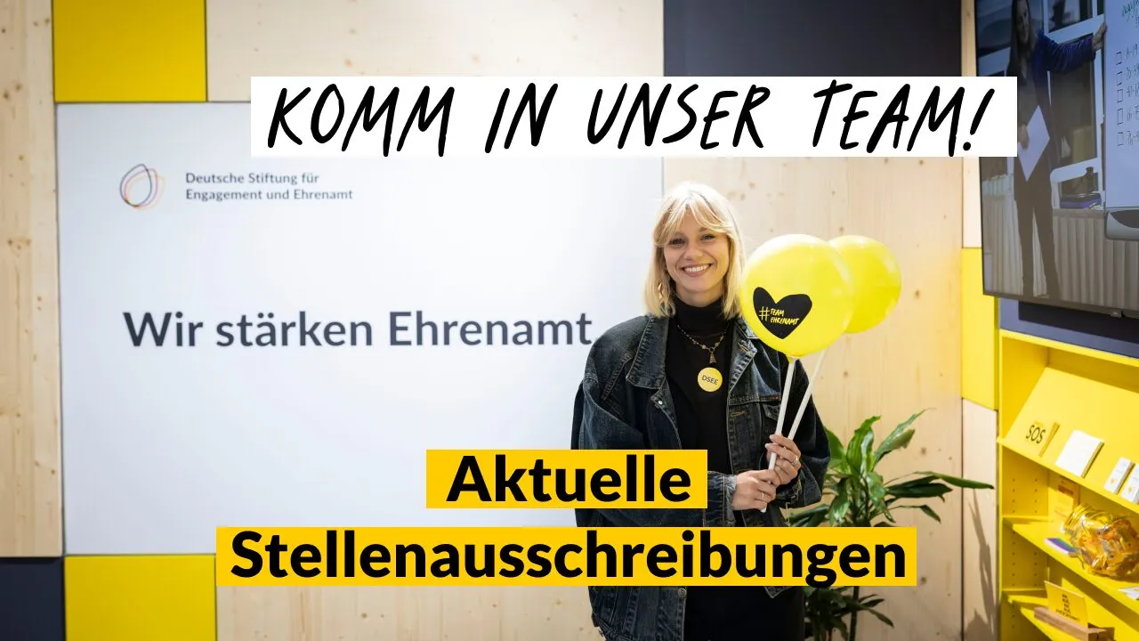 Foto einer DSEE-Kollegin vor einem DSEE-Poster mit dem Claim: Wir stärken Ehrenamt. Text: Komm in unser Team! Aktuelle Stellenausschreibungen