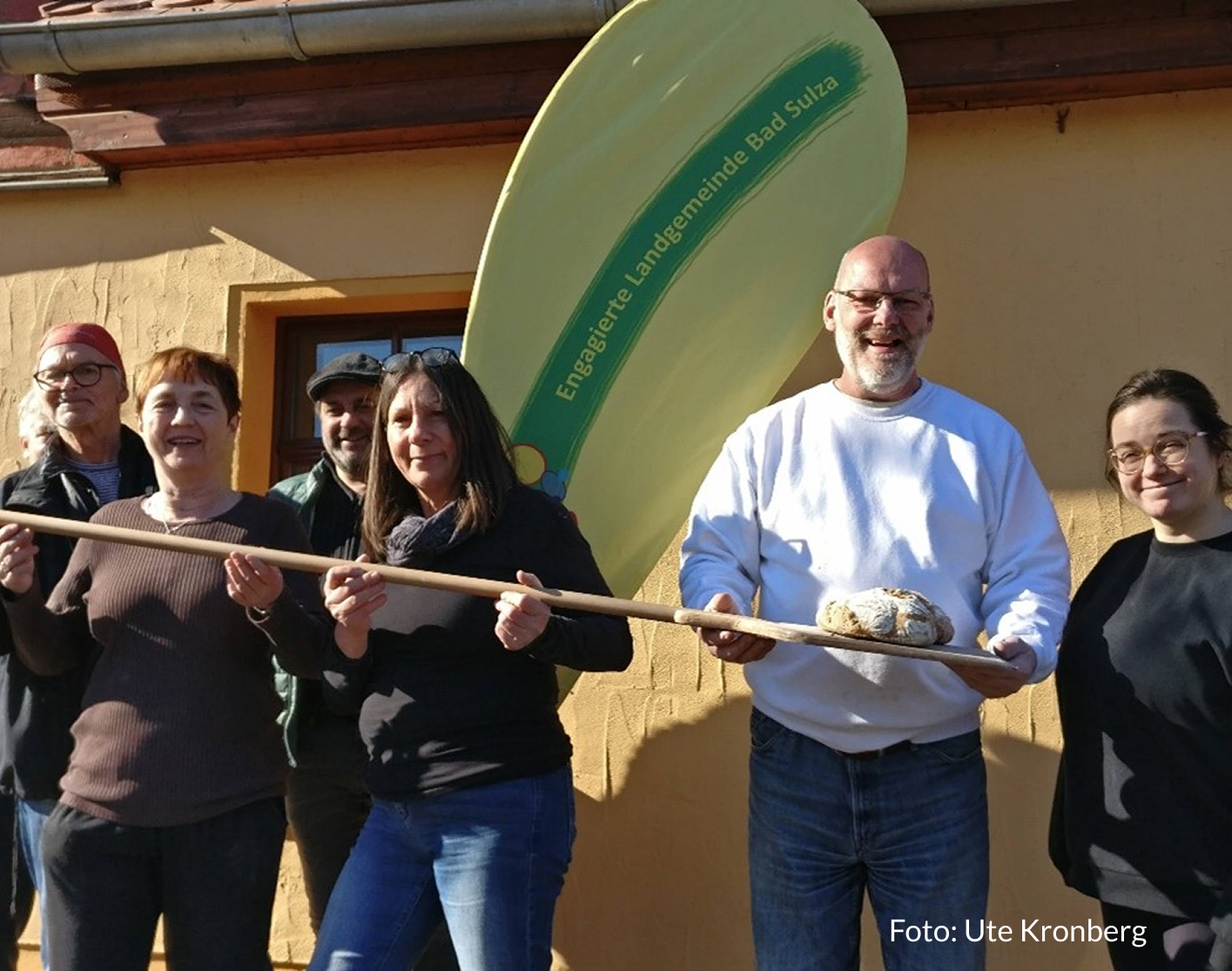 Mitglieder der Engagierten Landgemeinde Bad Sulza präsentieren ein selbstbebackenes Brot auf einer Brotschaufel