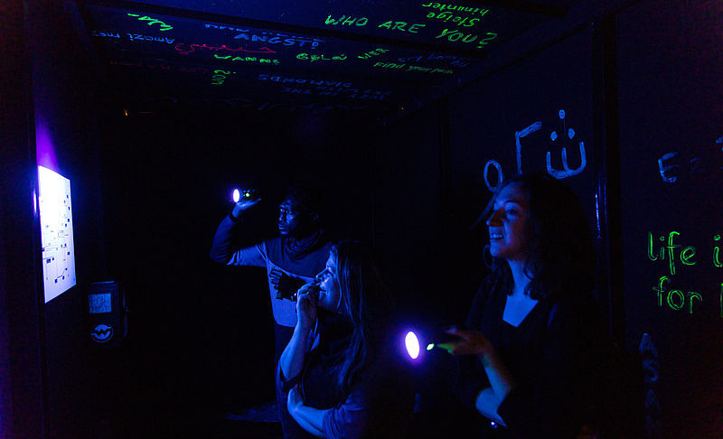Blick in den dunklen Escape-Room mit Besuchenden