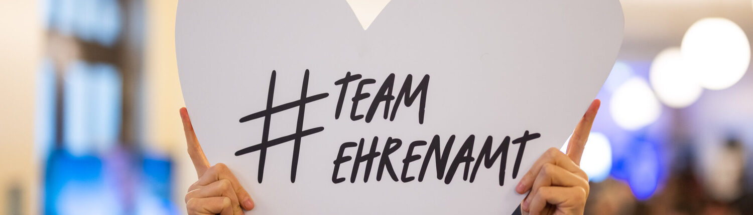 Hochgehaltenes weißes Her mit der Beschriftung "# Team Ehrenamt" (zusammengeschrieben)