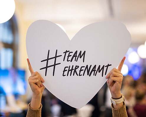 Hochgehaltenes weißes Her mit der Beschriftung "# Team Ehrenamt" (zusammengeschrieben)