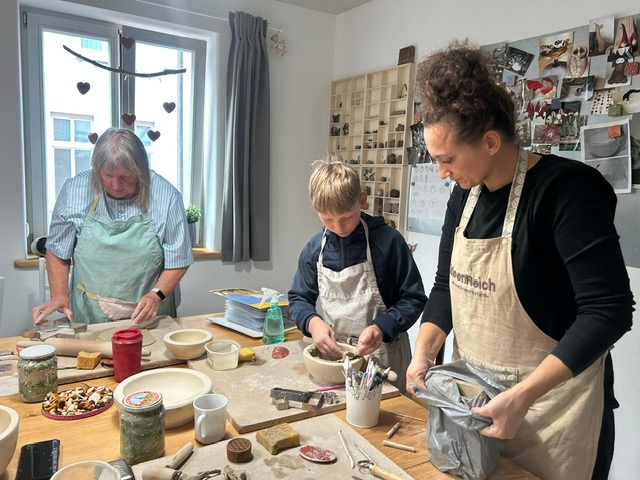 Dorfleben voller Kreativität | Buchholz | Mecklenburg-Vorpommern Drei Personen arbeiten zusammen an einem Tisch im Töpferkurs und formen gemeinsam Tonobjekte.